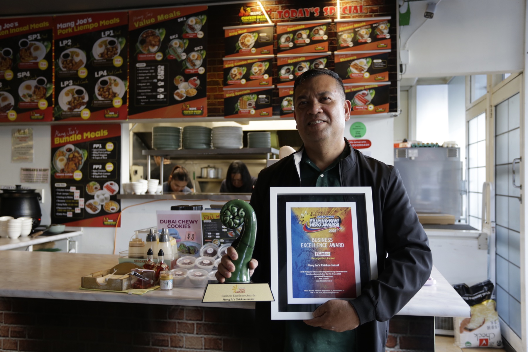 Mang Joe holding his business excellence award inside Mang Joe's Chicken Inasal